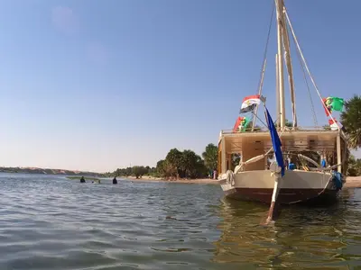 a boat sitting in the water on a beach at JJ Jamaica Felucca in Aswan