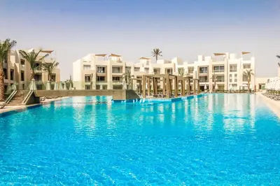 a large pool with blue water in front of buildings at Ollystays Mangroovy 2 BR Beach and Pool Free access in Hurghada