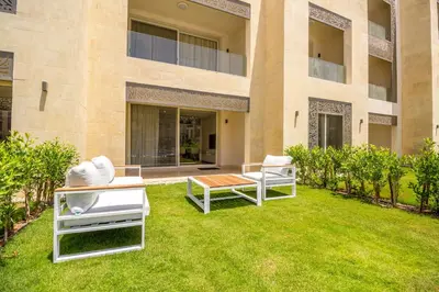 a yard with two lawn chairs and a building at Ollystays Mangroovy 2 BR Beach and Pool Free access in Hurghada