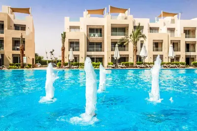 a pool in front of a hotel with water fountain at Ollystays Mangroovy 2 BR Beach and Pool Free access in Hurghada