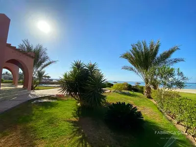 a lawn with palm trees in front of a building at FabbricaCasa Sea Front Villa, Oriental Coast in Marsa Alam City
