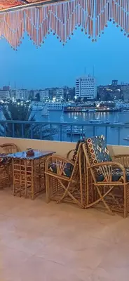 a balcony with chairs and tables and a view of a city at Masa Nubian House in Aswan