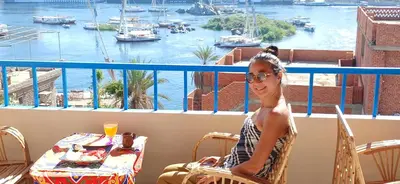 a woman sitting on a balcony with a view of a harbor at Masa Nubian House in Aswan