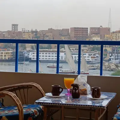 a table with a glass of orange juice and a view of a harbor at Masa Nubian House in Aswan