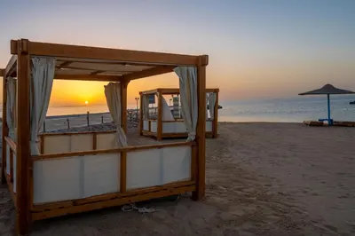 a couple of beds on the beach at sunset at New Eagles Aqua Park Resort in Hurghada