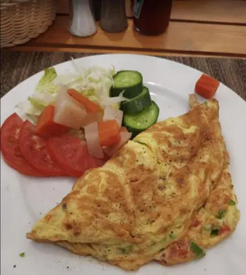 a white plate with a piece of omelet and vegetables at Tiba View - Unit no B15 - near ElGouna in Hurghada