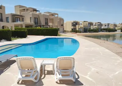 two chairs and a swimming pool in front of some apartments at Boho Chic - Scenic Lagoon View at Tawila, Gouna in Hurghada