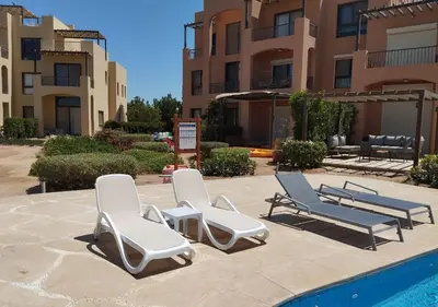 a group of lounge chairs next to a swimming pool at Boho Chic - Scenic Lagoon View at Tawila, Gouna in Hurghada
