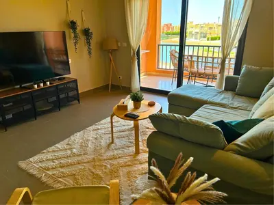a living room with a couch and a tv and a table at Boho Chic - Scenic Lagoon View at Tawila, Gouna in Hurghada