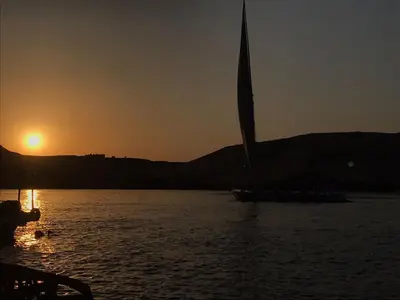 a sail boat in the water at sunset at Kafana Guest House Nile View in Aswan