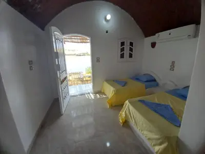 a room with two beds in a room with a door at Kafana Guest House Nile View in Aswan