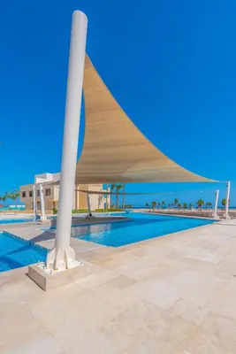 a swimming pool with a pavilion next to a building at Mangroovy 3BR Apartment Private Beach & Pool View in Hurghada