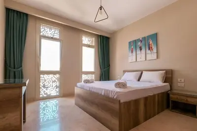 a bedroom with a large bed and two windows at Mangroovy 3BR Apartment Private Beach & Pool View in Hurghada