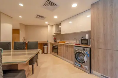 a kitchen with a table and a washing machine at Mangroovy 3BR Apartment Private Beach & Pool View in Hurghada