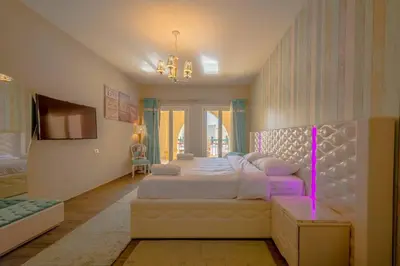 a large bedroom with a large bed with a pink lighting at Marina Mosaique 1 BR Apartment with Pool view in Hurghada