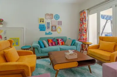 a living room with a blue couch and orange chairs at Marina Mosaique 1 BR Apartment with Pool view in Hurghada