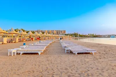 a row of chaise lounges on a beach at The Grand Hotel, Hurghada in Hurghada