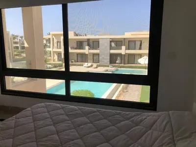 a bedroom with a view of a pool from a window at G cribs 2 BR sharing Pool in Hurghada
