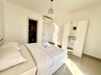 a white bedroom with a bed and a mirror at G cribs 2 BR sharing Pool in Hurghada