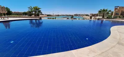 a swimming pool with blue tiles in a resort at Waterside Apartments, El Gouna - 1Bd Ground Floor in El Gouna