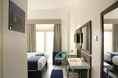 a hotel room with two beds and a table and chairs at Gloria Aqua Park Hotel in Aswan
