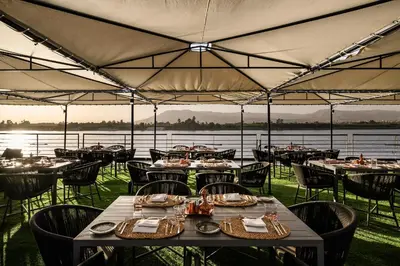 a restaurant with tables and chairs with a view of the water at Historia The Boutique Hotel Nile Cruise - Every Monday from Luxor for 04 & 07 Nights - Every Friday From Aswan for 03 & 07 Nights in Luxor