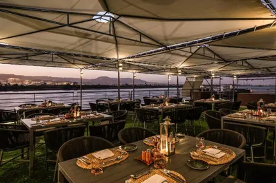 a restaurant with tables and chairs and a view of the water at Historia The Boutique Hotel Nile Cruise - Every Monday from Luxor for 04 & 07 Nights - Every Friday From Aswan for 03 & 07 Nights in Luxor