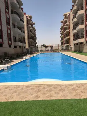 a large swimming pool in the middle of two apartment buildings at Kemet Apartment luxor in Luxor