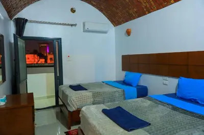 a bedroom with two beds with blue pillows at Jamaica Guest House in Aswan