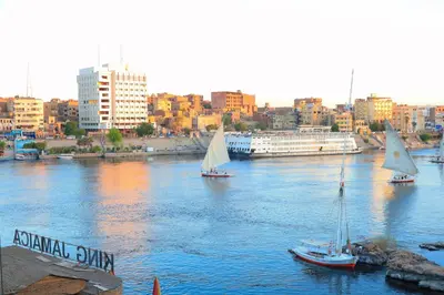 three sailboats on a river with a city in the background at Jamaica Guest House in Aswan