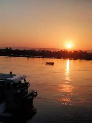 a sunset on a river with boats in the water at Nile queen Apartments for Rent in Luxor