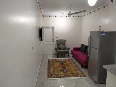 a living room with a red couch and a refrigerator at Nile queen Apartments for Rent in Luxor