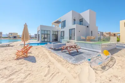 a house on the beach with a pool and an umbrella at Long Island Gouna 5BR Tawila Beach House & Pool in Hurghada