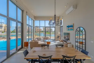 a dining room with a table and a living room with a pool at Long Island Gouna 5BR Tawila Beach House & Pool in Hurghada
