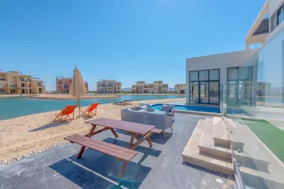 a patio with a picnic table and chairs on the beach at Long Island Gouna 5BR Tawila Beach House & Pool in Hurghada
