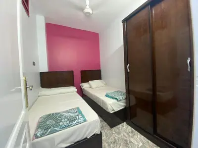two beds in a small room with pink walls at ALRahman Building in Aswan