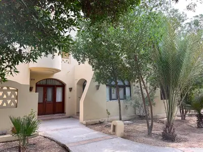 a white house with a brown door and trees at El Gouna, Red Sea, Egypt, West Golf 2 Bedroom Flat in Hurghada