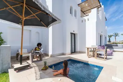 a woman sitting in a pool next to a house at Sunrise Tucana Resort Grand Select in Hurghada