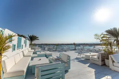 a patio with tables and chairs and palm trees at Sunrise Tucana Resort Grand Select in Hurghada