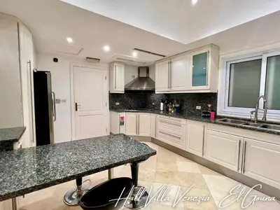 a kitchen with white cabinets and a granite counter top at Hill Villa Venezia El Gouna: pool, beach & WiFi in Hurghada