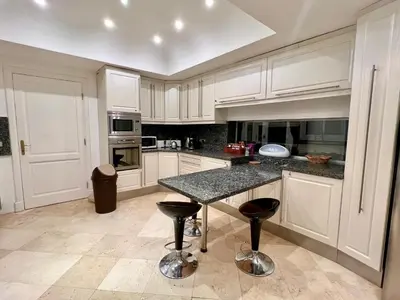 a kitchen with white cabinets and a table with stools at Hill Villa Venezia El Gouna: pool, beach & WiFi in Hurghada