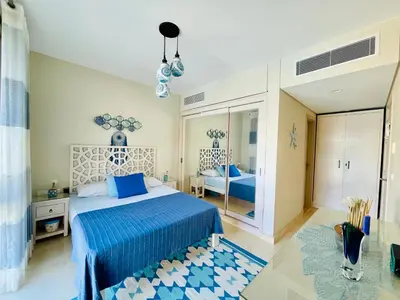 a bedroom with a blue bed and a mirror at Kitesurfer Shared House, Pool View & Beach Access in Hurghada