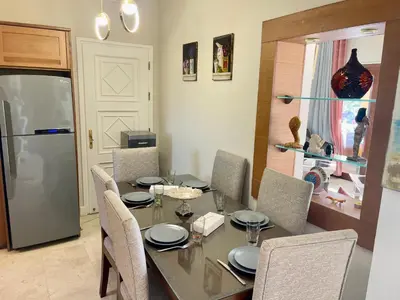 a dining room with a table with chairs and a refrigerator at Y 140 wast golf heated private pool in Hurghada