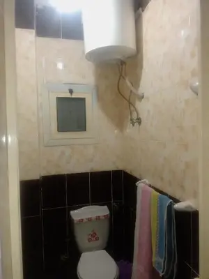a bathroom with a toilet and a lamp and towels at App11- BELAL - Enjoy the privacy of staying in a quiet apartment with free Wi-Fi as your complete second home in the heart of Hurghada in Hurghada