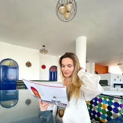 a woman is reading a paper in a room at NUB INN in Aswan