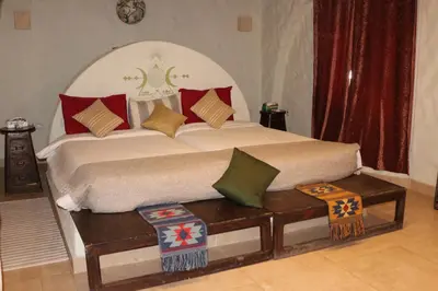a bedroom with a large bed and a bench with pillows at Artika Wadi Kiki Hotel in Aswan