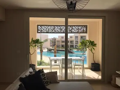a living room with a view of a table and a pool at Jutta Deluxe 2,5-Bedroom-Apartment Mangroovy-M10 El Gouna in Hurghada