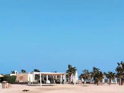 a view of a beach with palm trees and a building at Jutta Deluxe 2,5-Bedroom-Apartment Mangroovy-M10 El Gouna in Hurghada