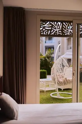 a bedroom with a sliding glass door with a chair outside at Mangroovy apartament El gouna in Hurghada