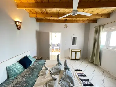 a room with a bed and a ceiling fan at Nefertarie Guest House in Luxor